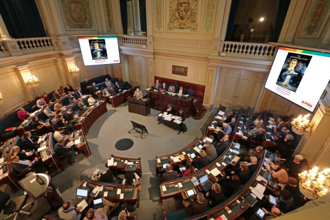 Onze aanklacht tegen de 'neverending story' van besparingen geprojecteerd in de provincieraad. Het diasjabloon toont ook de nieuwe PVDA-kleuren.